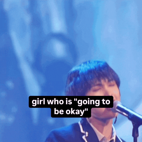 a man singing into a microphone with the words " girl who is " going to be okay " below him