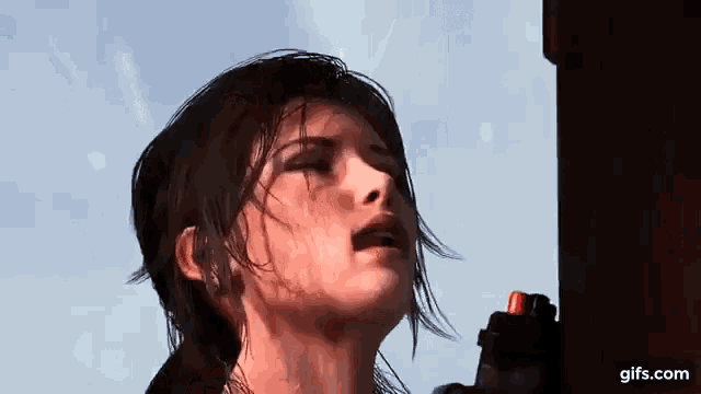 a woman is spraying water on her face while standing next to a wooden pole .