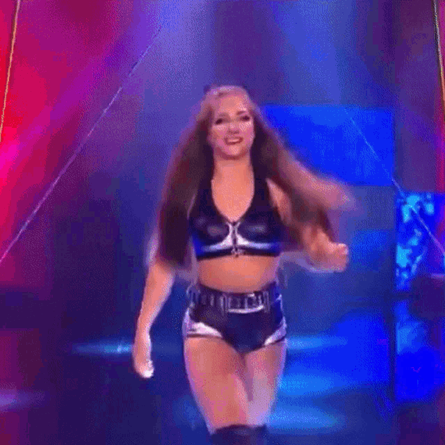 a female wrestler is standing on a stage with her hair in the air .