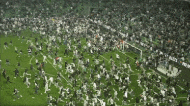 a crowd of people running on a soccer field with a sign that says " allets "