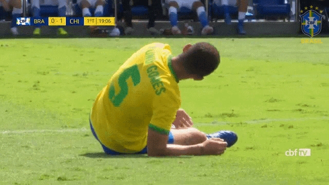 a soccer player with the number 5 on his back sits on the grass