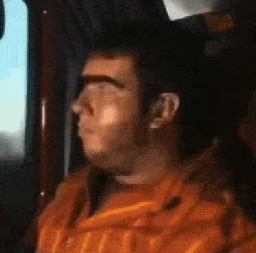 a man with a beard is looking out of a window .