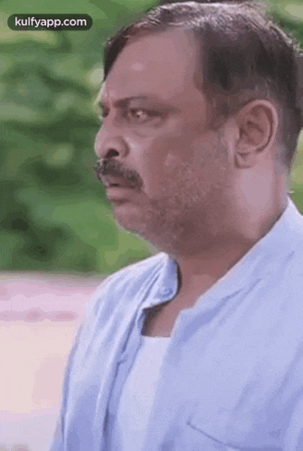 a man with a beard and mustache is making a funny face and looking at the camera .