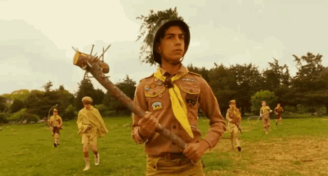 a boy scout with a yellow scarf around his neck holding a stick