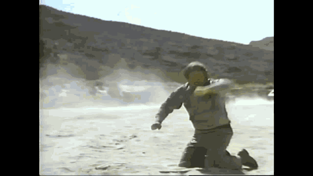 a man is kneeling down in the dirt and throwing something in the air