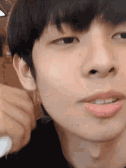 a close up of a young man 's face with his mouth open and a pink lip .