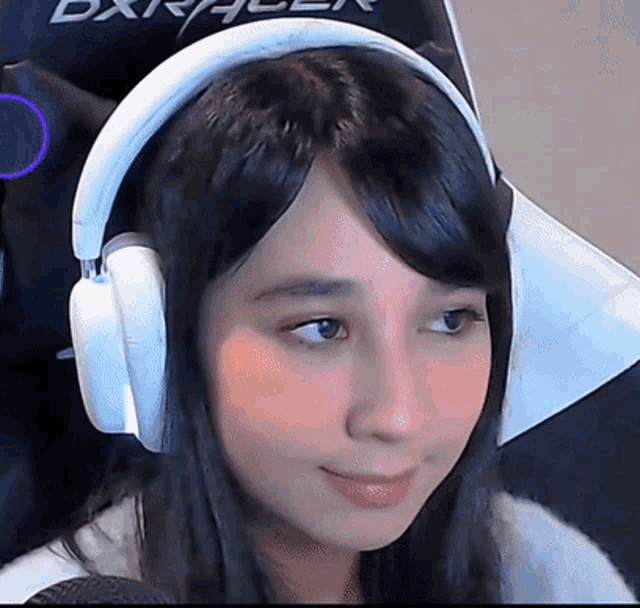 a woman wearing headphones is sitting in a chair that says dxracer on it