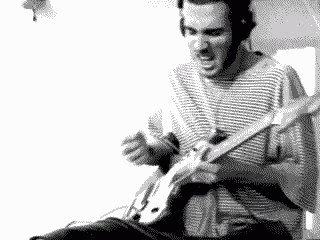 a man in a striped shirt is playing a guitar in a black and white photo .