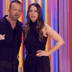 a man and a woman standing next to each other in front of a colorful backdrop