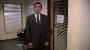 a man in a suit and tie is standing in front of a door holding a cane .