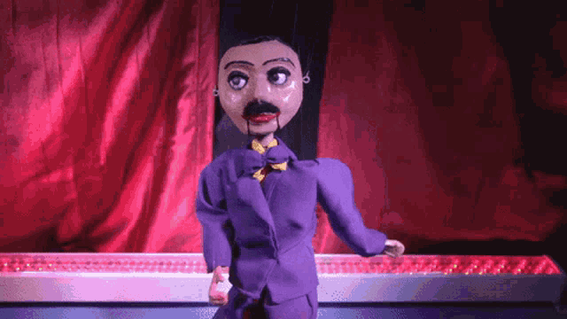 a puppet is wearing a purple suit and a bow tie