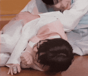 two people are laying on the floor and one has a ring on her finger