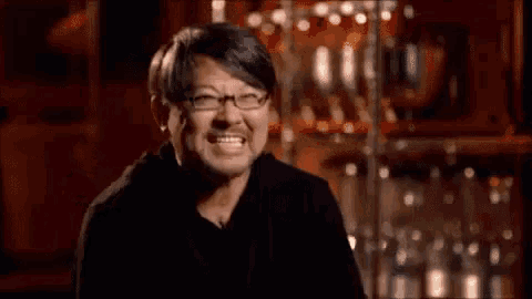 a man wearing glasses and a black shirt is making a funny face .