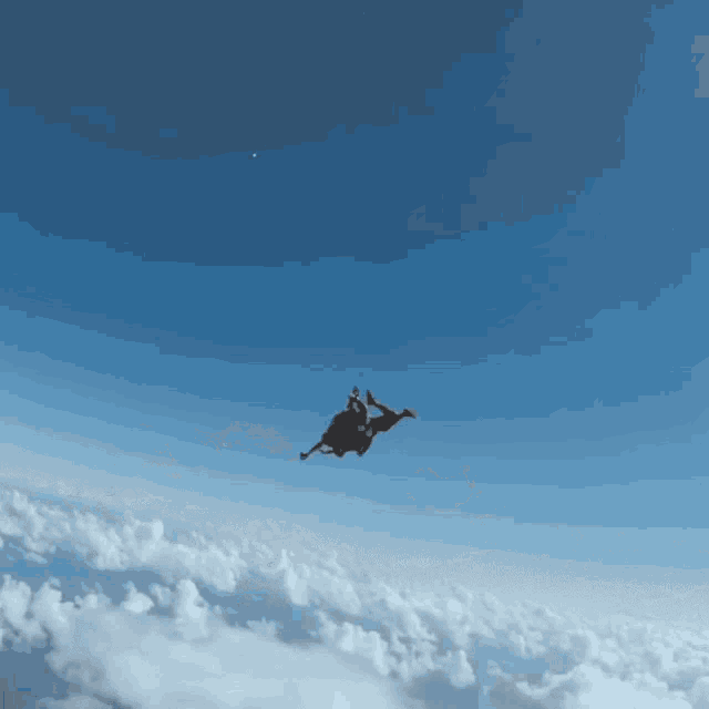a person is falling through the air with a blue sky and clouds in the background