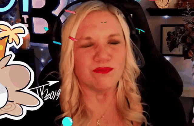 a blonde woman wearing headphones has a sticker on her forehead that says t22019