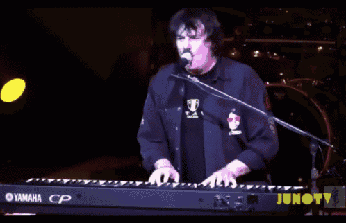 a man is singing into a microphone while playing a keyboard that says yamaha on it