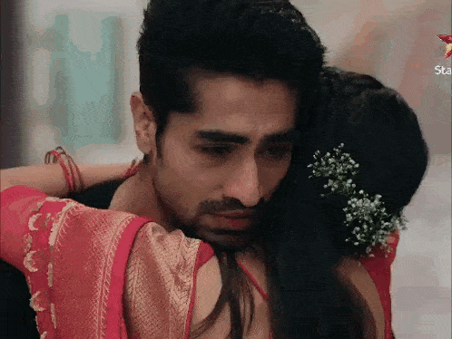 a man is hugging a woman who is wearing a red dress