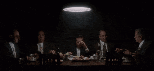 a group of men sitting around a table with a plate of food