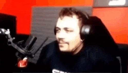 a man is wearing headphones and sitting in front of a microphone .