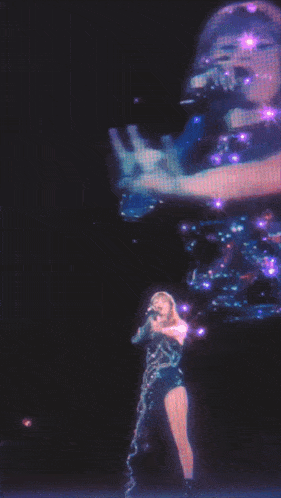 a woman is singing into a microphone while another woman is standing behind her
