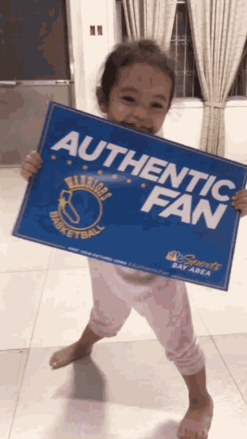 a little girl holds a sign that says authentic fan