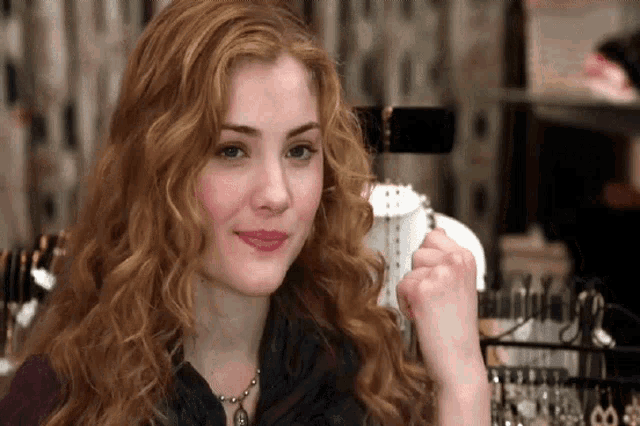 a woman with curly hair is looking at a necklace on display