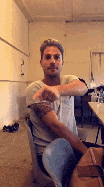 a man with a tattoo on his arm is sitting in a chair stretching his arm