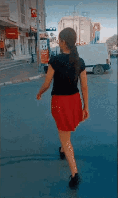 a woman in a red skirt is crossing a street