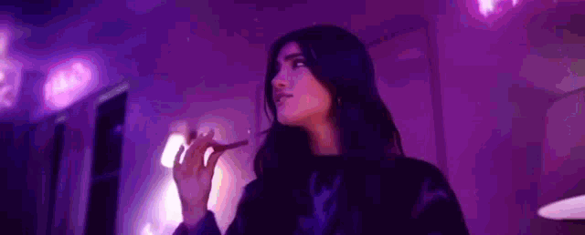 a woman is standing in a dark room with purple lights .