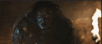 a monster is standing in front of a fireplace with a torch .