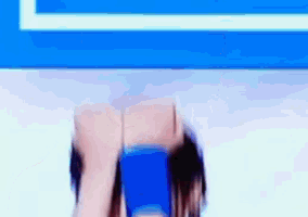 a woman in a blue shirt is standing in front of a blue and white wall .
