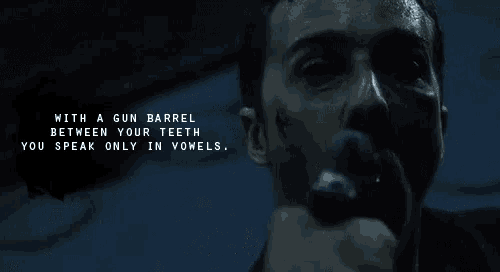 a man holding a gun with a quote between his teeth