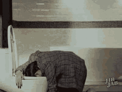 a woman is laying on a toilet with her head in it .