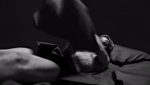 a black and white photo of a man laying on a bed wearing calvin klein underwear