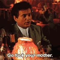a man in a suit is sitting at a table with a lamp that says go fuck your mother
