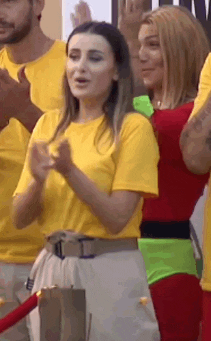 a woman in a yellow shirt is standing next to a woman in a red dress .
