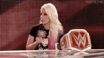 a woman is sitting at a table with a microphone in her hand .
