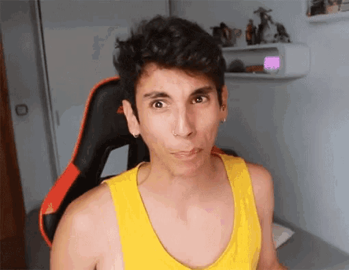 a man wearing a yellow tank top is sitting in a gaming chair