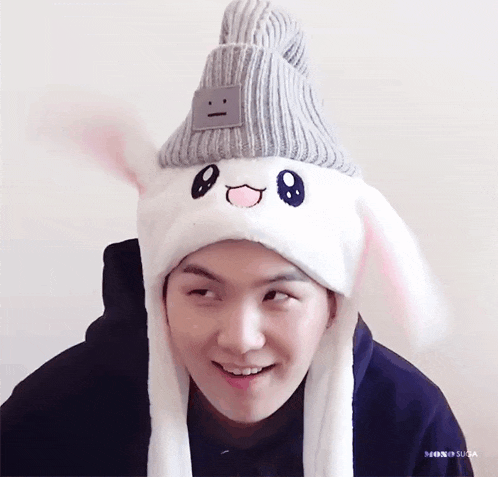 a man wearing a hat with bunny ears and a smiley face on it