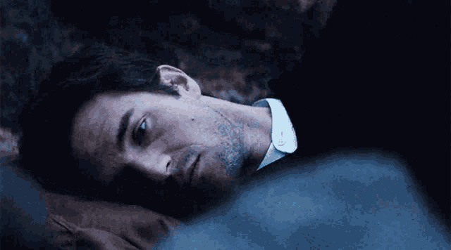 a man in a black shirt and white collared shirt is laying down
