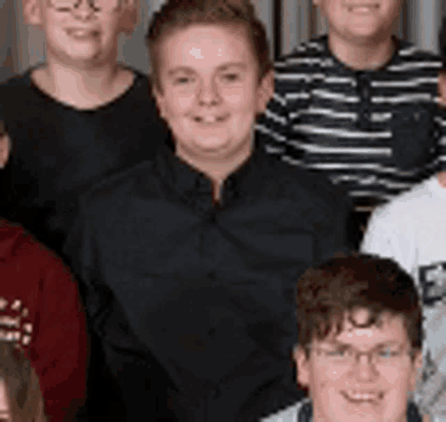 a group of young people posing for a picture with one wearing glasses