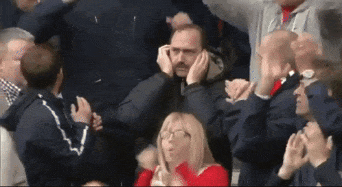 a man with a mustache is covering his ears with his hands