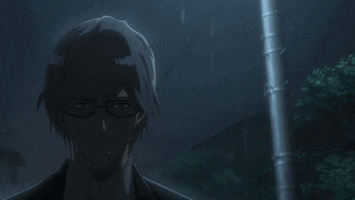 a man wearing glasses is standing in the dark