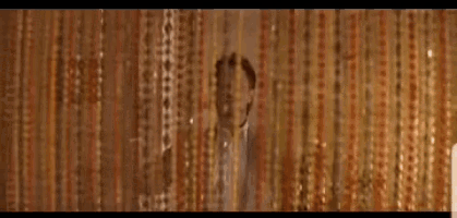 a man is standing in a room with his arms outstretched and looking out a window .