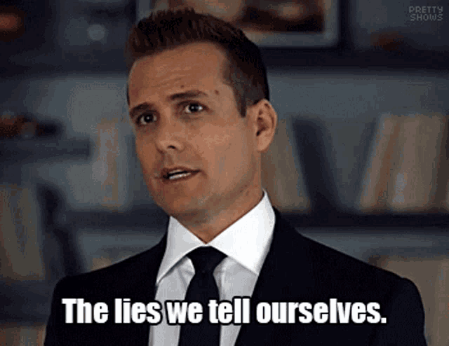 a man in a suit and tie is standing in front of a bookshelf and saying `` the lies we tell ourselves . ''