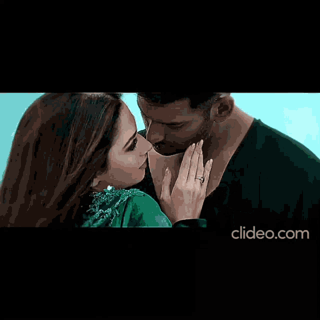 a close up of a man kissing a woman on the cheek with clideo.com at the bottom