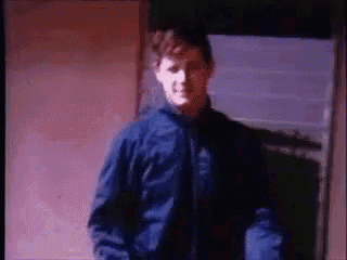 a man in a blue jacket is standing in front of a door in a dark room .