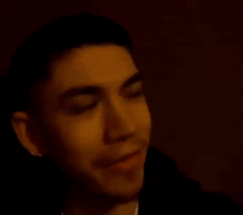 a close up of a man 's face in a dark room with his mouth open .