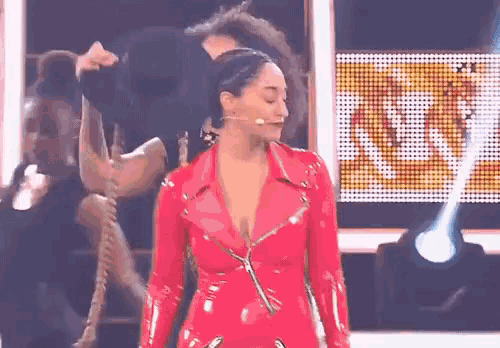 a woman in a red leather suit is standing on a stage with a microphone .