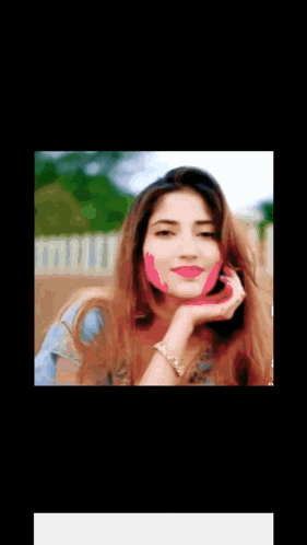 a woman with pink paint on her face is talking on a phone